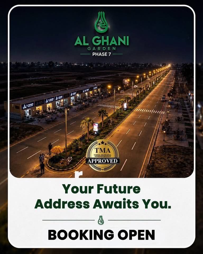 Night view of Al Ghani Garden Phase 7 main boulevard with street lights and commercial shops